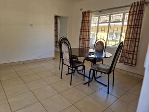 a dining room with a table and chairs and a window at Cosy Harare Haven Cottage in Harare