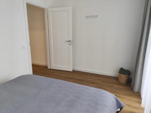 a white room with a bed and a door at Stay Rokiškis apartments in Rokiškis