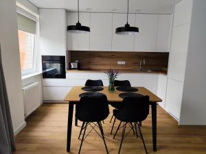 a kitchen with a wooden table and black chairs at Stay Rokiškis apartments in Rokiškis +14 photos