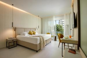 una camera da letto con un grande letto bianco e una scrivania di Ambasciatori Suite Hotel a Sottomarina
