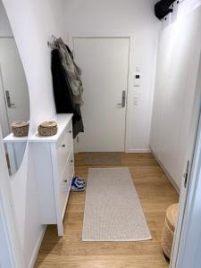 a hallway with white cabinets and a mirror and a door at Heart of Aarhus, modern apartment and paid parking nearby in Aarhus