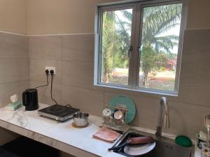 a kitchen counter with a sink and a window at Simply Studio Hotel Parit Raja in Batu Pahat