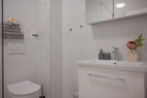 a white bathroom with a sink and a toilet at Holiday apartments by the sea in Funtana +56 photos