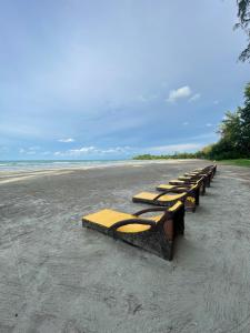 une rangée de bancs assis sur une plage dans l'établissement Desaru beach stay Tiara residences, à Bandar Penawar
