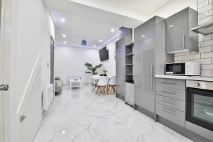 カーディフにあるModern 2 Bedroom House in Central Cardiffの白いキッチン(テーブル、電子レンジ付)