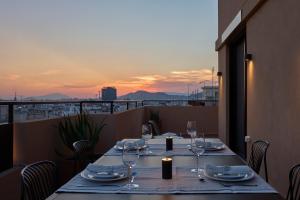 a table with wine glasses on a balcony with the sunset at Ikima Living in Piraeus