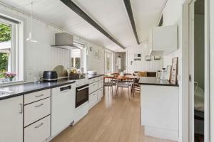 une cuisine avec des placards blancs et une salle à manger dans l'établissement Lovely Cottage Close To Beach And Nature, à Yderby