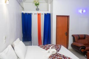 ein Schlafzimmer mit bunten Vorhängen, einem Bett und einem Stuhl in der Unterkunft New Hotel Sossa in Cotonou + 40 Fotos