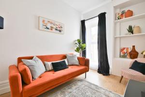 a living room with an orange couch with pillows at Beautifully Designed Flat with Full Amenities in Cardiff