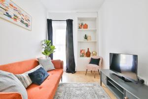 a living room with a orange couch and a flat screen tv at Beautifully Designed Flat with Full Amenities in Cardiff