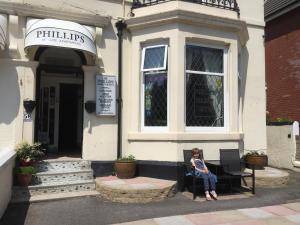 a woman sitting in a chair outside of a building at Phillips Apartments in Blackpool