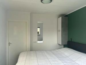 a bedroom with a white bed and a green wall at Huisje Meerweg in Rohel