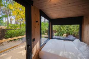 a bed in a room with a large window at Cabañas del bosque Sacedón in Sacedón