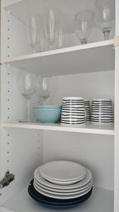 a white cabinet with plates and wine glasses on it at Himos,Halli, Vehkaojan viihtyisä yksiö,A7 in Halli
