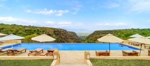 a swimming pool with chairs and umbrellas at Africa Safari Manyara Escarpment in Mto wa Mbu