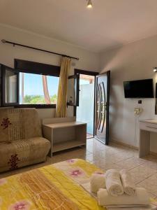 a bedroom with a bed and a couch and a tv at Sissy's Suites San Antonio Beach Potos Thassos in Potos