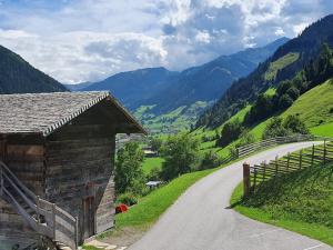 a barn on a road with mountains in the background at Reitbauernhof in Grossarl