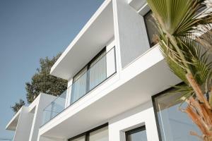 a white house with glass windows and a palm tree at Soléa Villa in Rrushkull