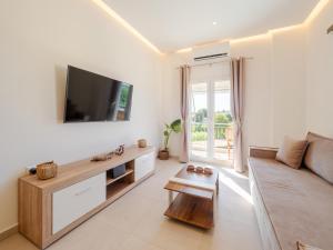a living room with a couch and a flat screen tv at Terra Residence in Ágios Rókkos