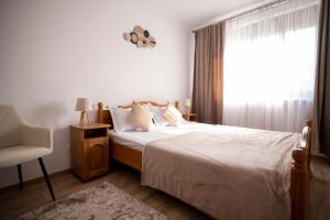 a bedroom with a bed and a chair and a window at Aly&Emy 2 in Caransebeş