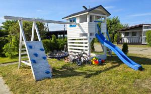 a playground with a blue slide and a play house at Szumi domek in Kołobrzeg