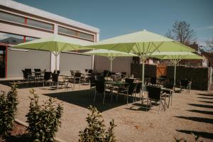 a patio with tables and chairs under green umbrellas at Campus Bad Kissingen in Bad Kissingen