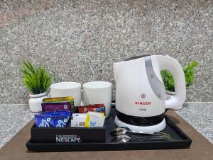 a white coffee maker sitting on a black tray at The Mall Ethos - On Mall Road - Kitchen - Sleeps 4 in Shimla +4 photos