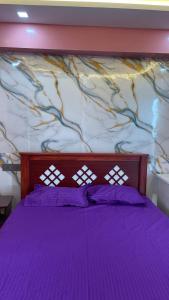 a bedroom with a purple bed with a wall at Yellow Bliss Homestay in Coimbatore