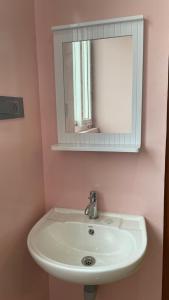 a bathroom with a white sink and a mirror at Yellow Bliss Homestay in Coimbatore +3 photos