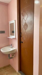 a bathroom with a sink and a wooden door at Yellow Bliss Homestay in Coimbatore
