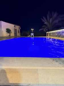ein blauer Pool in der Nacht mit einem Stuhl in der Unterkunft قريه المروه الساحل الشمالي فيلا 5 غرف وحمام سباحه خاص in Dawwār ‘Abd Allāh