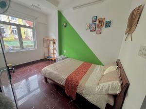 a bedroom with a bed with a green wall at Hotel Hưng Phát in Da Lat