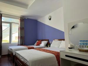 a hotel room with two beds and a mirror at Hotel Hưng Phát in Da Lat