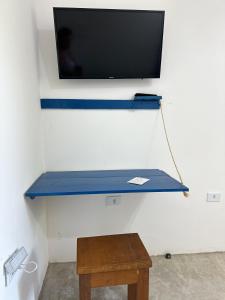 a tv hanging on a wall with a blue table at Casa Oxum Cumuru in Cumuruxatiba