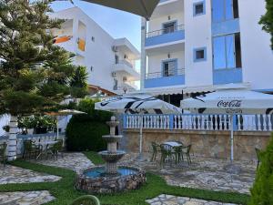 a fountain with chairs and umbrellas next to a building at Esmeralda Hotel & Restaurant in Ksamil