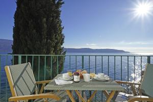 a table with cups and coffee on a balcony with the ocean at Villa Vinessa in Toscolano Maderno