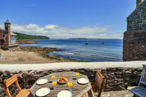 a wooden table with a plate of food on the beach at Finest Retreats - April Cottage in Cawsand