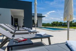 a group of lounge chairs and umbrellas next to a swimming pool at Villa Valinka Design in Golaš