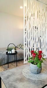 a room with a bed and a table with red flowers at Apartamentai prie Akropolio gražiu vaizdu į miesta in Klaipėda