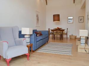 a living room with two blue chairs and a table at Printmakers Cottage in Bellanoch