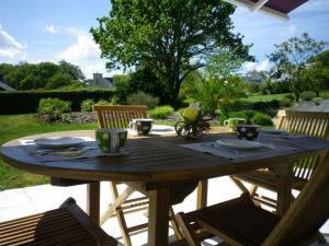 a wooden table with cups and saucers on a patio at Les jardins de kerarzic in Ploubazlanec