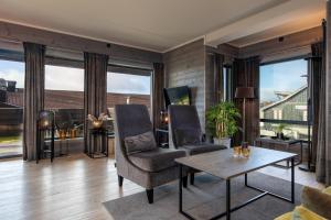 a living room with two chairs and a table and large windows at Riddertunets glimt in Beitostøl
