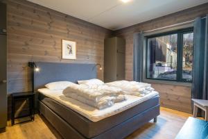 a bed in a room with a wooden wall at Riddertunets glimt in Beitostøl