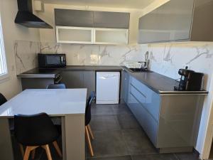a kitchen with blue cabinets and a white table at Appartement avec jardin 4 personnes in Fréjus +2 photos