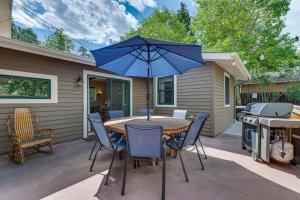 un tavolo e sedie con ombrellone blu su un patio di Private Hot Tub - Riverfront Cabin In Estes Park! a Estes Park