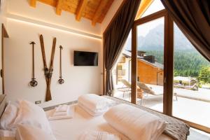 a bedroom with a bed and a large window at Maison Boutique Private Chalets & Spa in Sappada