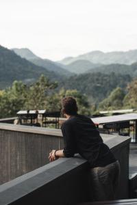 a man sitting on a ledge looking at the mountains at Silverback Lodge in Buhoma