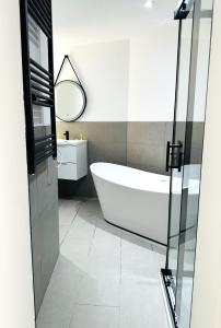 a bathroom with a bath tub and a mirror at Shoreditch Luxe in London