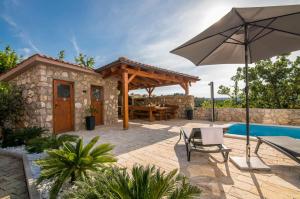 a patio with a table and an umbrella and a pool at Apartment TRIES 5 with heated pool and sea view in Klimno