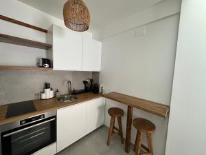 a kitchen with white cabinets and a sink and stools at VMJ side sea view in Perea